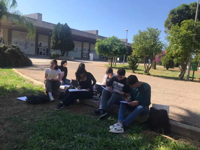 “Group of students sketching and writing near the RKIF walkway during community event”